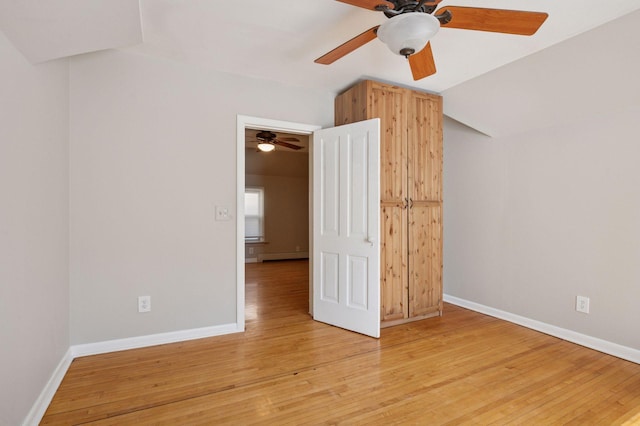 unfurnished bedroom featuring light wood-type flooring, baseboards, ceiling fan, and a baseboard heating unit