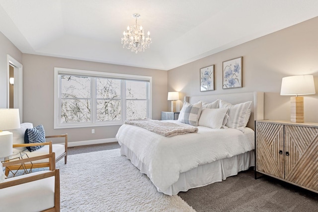 bedroom with a tray ceiling, a chandelier, dark colored carpet, and baseboards