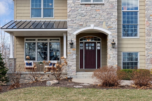 doorway to property with stone siding, a standing seam roof, and metal roof