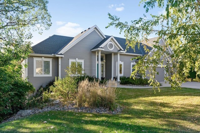 view of front of house with roof with shingles, a front lawn, and driveway