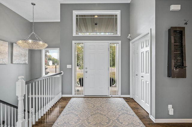 entrance foyer with a chandelier, a towering ceiling, baseboards, and dark wood-type flooring