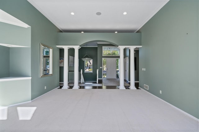 carpeted empty room featuring arched walkways, baseboards, ornate columns, and recessed lighting