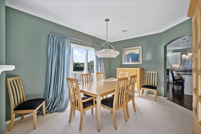 dining room with an inviting chandelier, carpet floors, crown molding, baseboards, and arched walkways