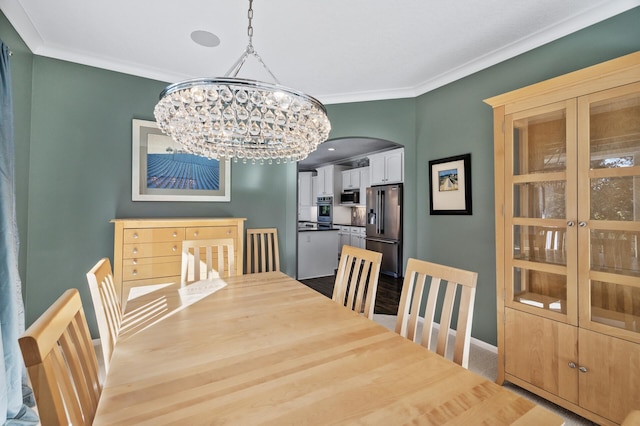 dining area featuring an inviting chandelier, ornamental molding, arched walkways, and baseboards