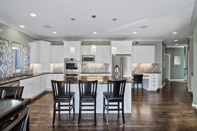 kitchen with a sink, stainless steel appliances, white cabinets, decorative backsplash, and ornamental molding