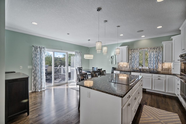 kitchen featuring black electric stovetop, dark wood finished floors, a center island, and a wealth of natural light