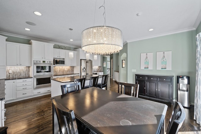 dining area with a notable chandelier, recessed lighting, ornamental molding, arched walkways, and dark wood-style floors