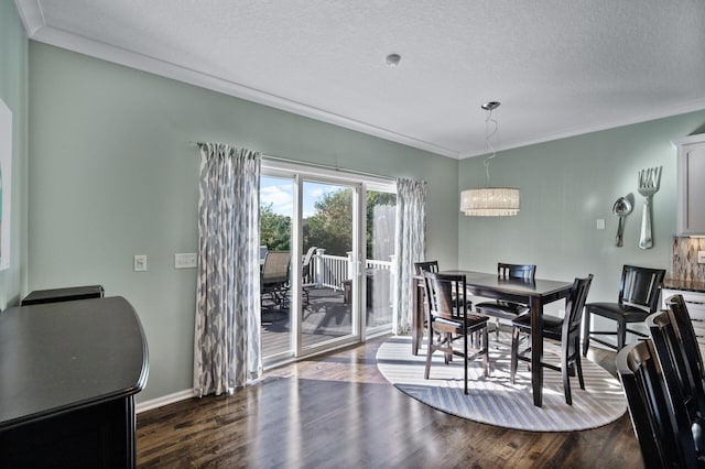 dining room with ornamental molding, a textured ceiling, dark wood-type flooring, a notable chandelier, and baseboards