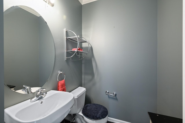 half bath with toilet, baseboards, and a sink