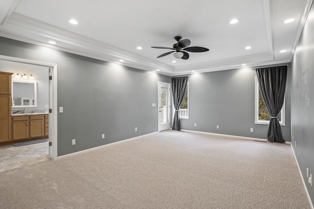 spare room with crown molding, baseboards, a raised ceiling, ceiling fan, and light colored carpet