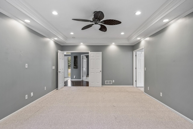 carpeted spare room featuring ceiling fan, ornamental molding, a raised ceiling, and visible vents