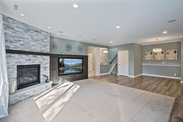 unfurnished living room with ornamental molding, visible vents, stairs, wood finished floors, and a fireplace