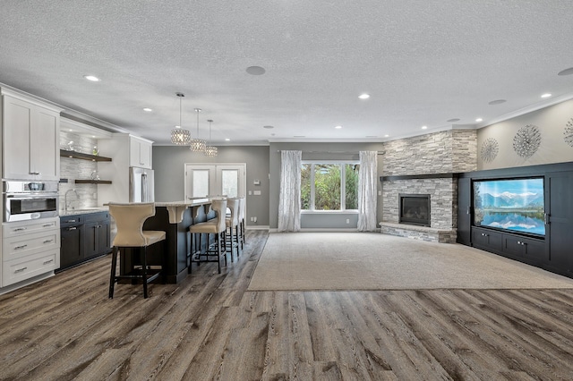 kitchen featuring a breakfast bar, open shelves, a textured ceiling, dark wood-type flooring, and appliances with stainless steel finishes