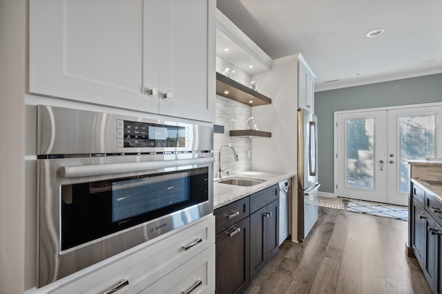 kitchen with a sink, open shelves, dark wood-type flooring, backsplash, and appliances with stainless steel finishes