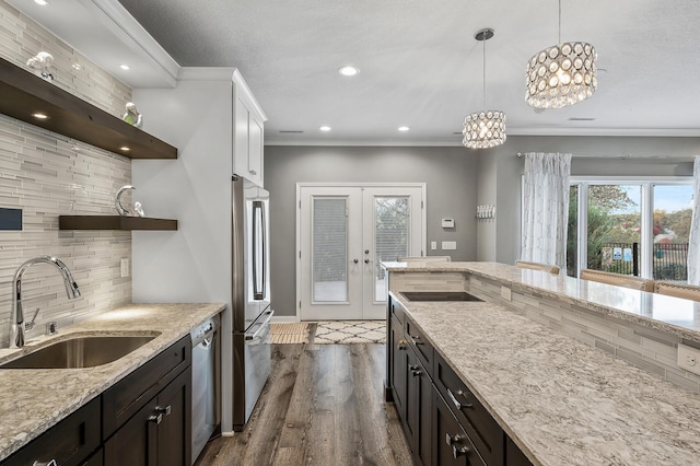kitchen with a sink, stainless steel appliances, tasteful backsplash, open shelves, and hanging light fixtures