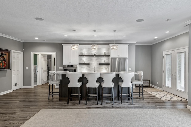 kitchen featuring a spacious island, dark wood-type flooring, white cabinets, baseboards, and appliances with stainless steel finishes
