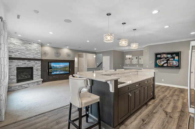kitchen with dark brown cabinets, a kitchen breakfast bar, dark wood-style flooring, ornamental molding, and recessed lighting
