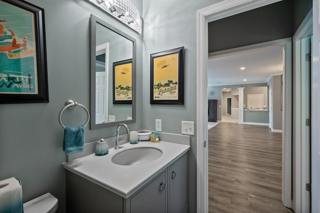 bathroom featuring recessed lighting, toilet, ornamental molding, vanity, and wood finished floors