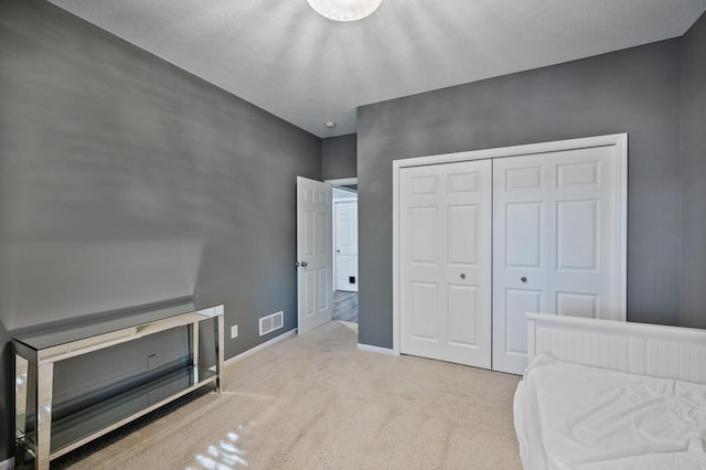 carpeted bedroom featuring baseboards, a closet, and visible vents