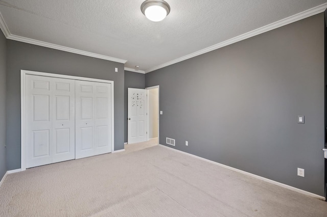 unfurnished bedroom with a closet, a textured ceiling, carpet, visible vents, and crown molding