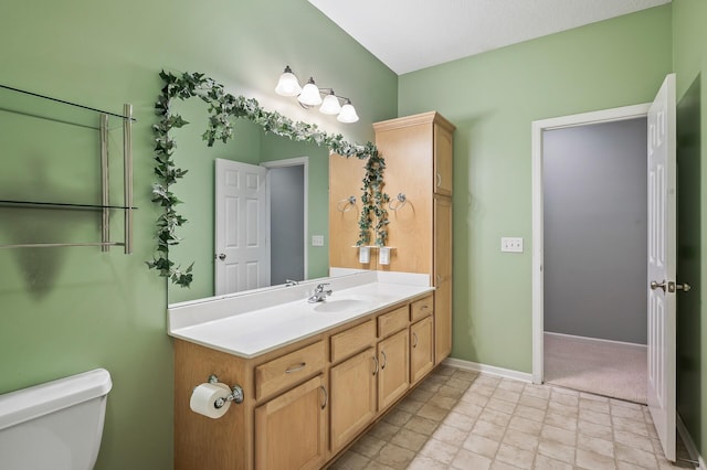 half bathroom with vanity, toilet, and baseboards