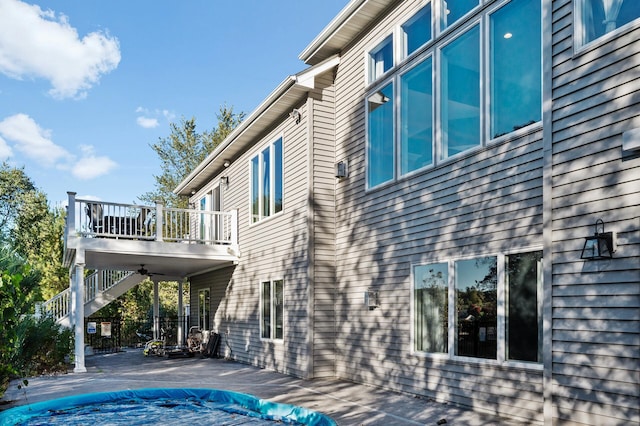 view of property exterior featuring a balcony, a fenced in pool, stairs, a patio area, and a wooden deck