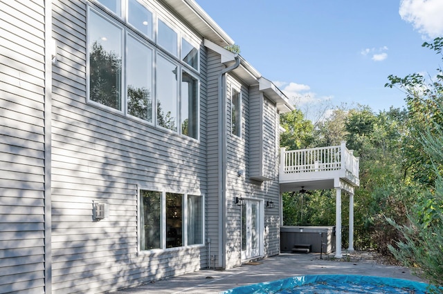 view of property exterior featuring a hot tub, a covered pool, and a patio area