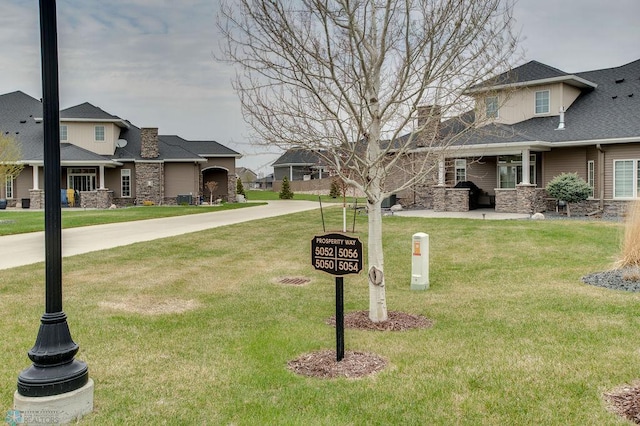 exterior space with roof with shingles, a chimney, a front lawn, and stone siding