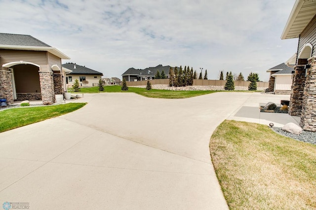 view of yard featuring fence, driveway, and a residential view
