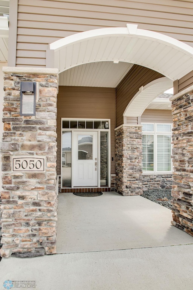 view of exterior entry with stone siding and a porch