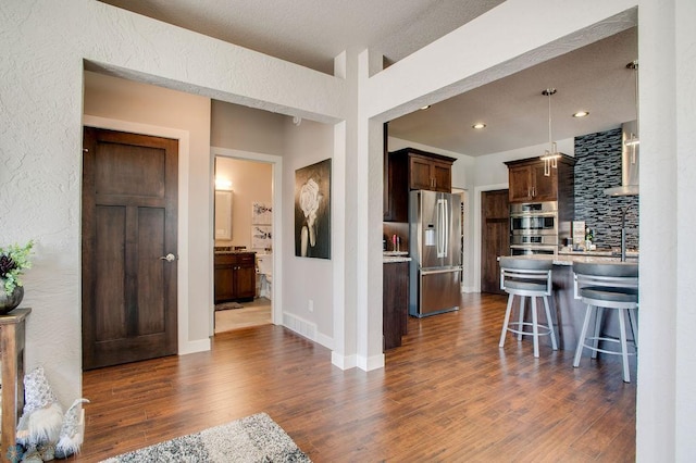 kitchen with a breakfast bar area, stainless steel appliances, visible vents, dark wood-type flooring, and light countertops