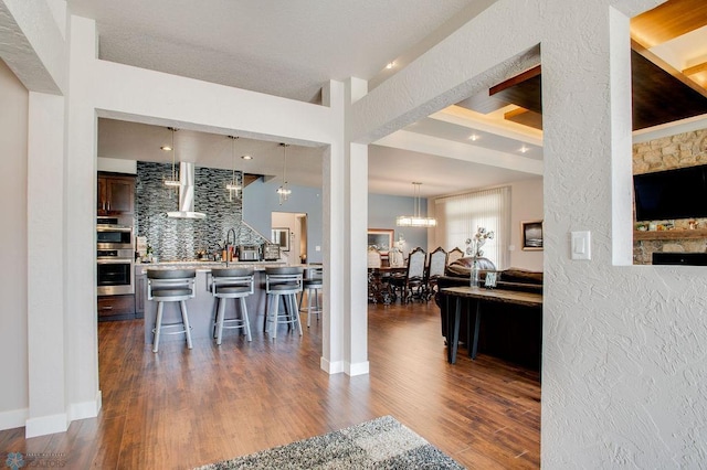dining area featuring a chandelier, a textured wall, and dark wood-type flooring