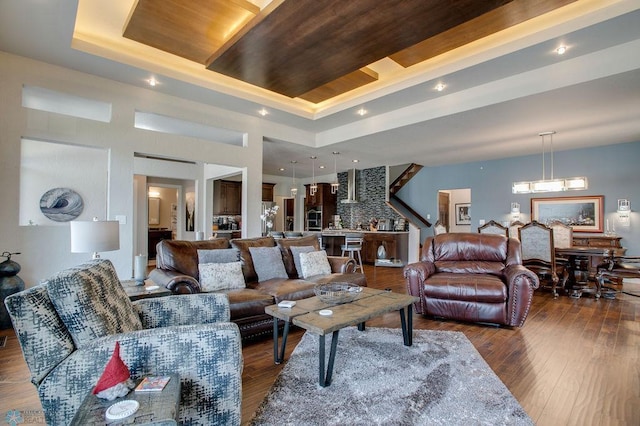 living area featuring a raised ceiling, a notable chandelier, and hardwood / wood-style flooring