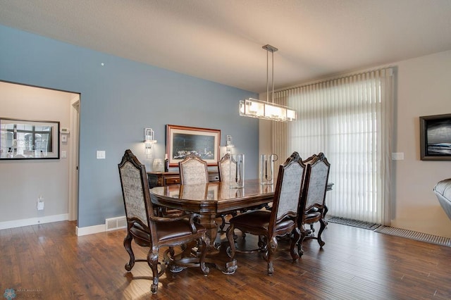 dining room with baseboards, a chandelier, visible vents, and wood finished floors