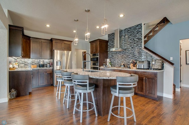 kitchen with backsplash, a center island with sink, light stone countertops, and appliances with stainless steel finishes