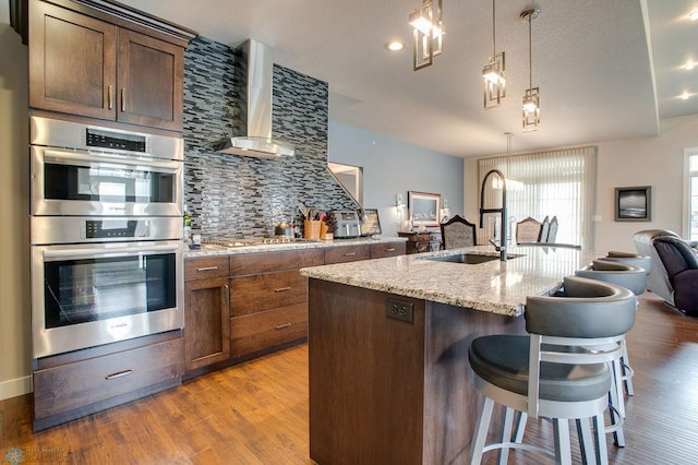 kitchen featuring appliances with stainless steel finishes, a sink, open floor plan, tasteful backsplash, and an island with sink