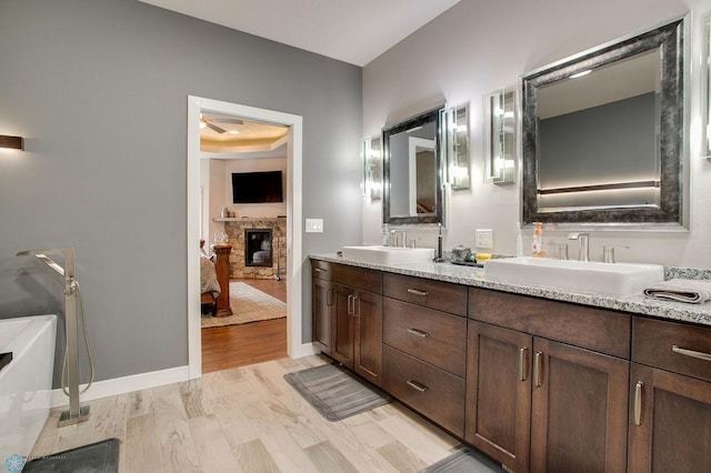 ensuite bathroom with a sink, double vanity, ensuite bathroom, and wood finished floors
