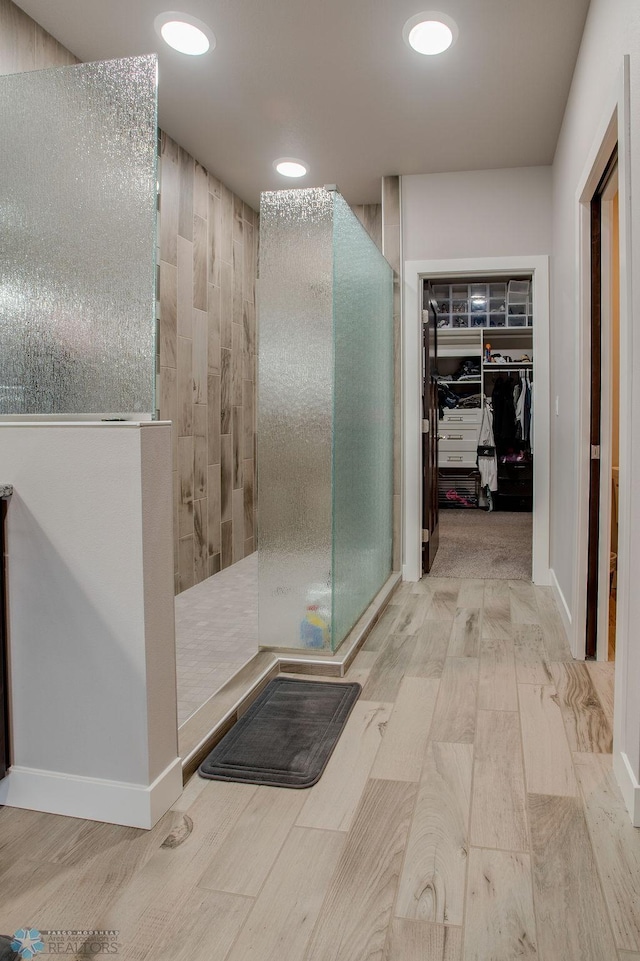 bathroom with a walk in closet, wood finished floors, recessed lighting, and a walk in shower