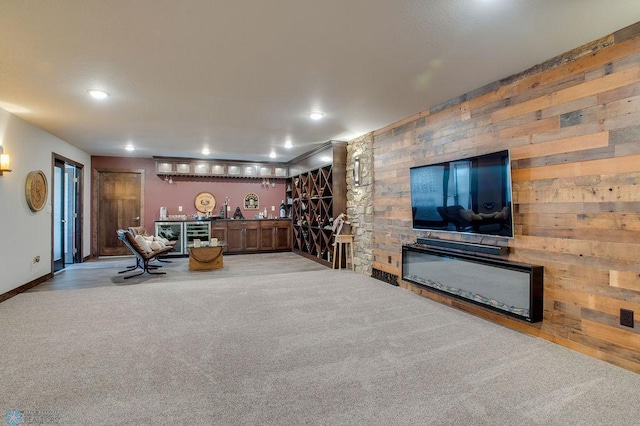 living room featuring carpet, indoor bar, baseboards, wooden walls, and recessed lighting