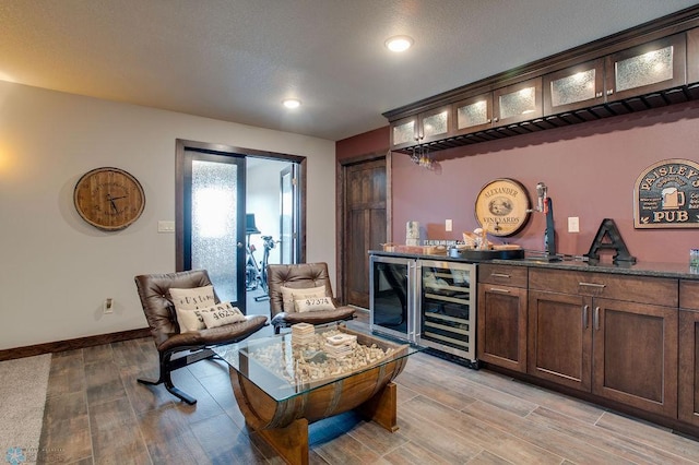 bar with wine cooler, a bar, recessed lighting, baseboards, and light wood finished floors