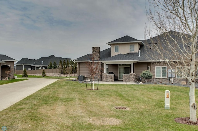 view of front of house featuring central AC unit, a chimney, a front lawn, and stone siding