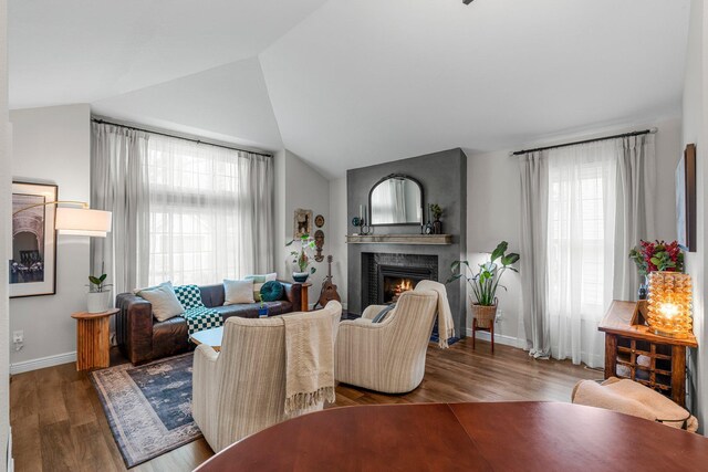 95 Olympic Cir, Chanhassen, MN 55317 - living area featuring a lit fireplace, healthy amount of natural light, vaulted ceiling, baseboards, and wood finished floors