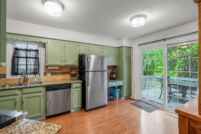 95 Olympic Cir, Chanhassen, MN 55317 - kitchen with stainless steel appliances, green cabinets, a sink, light wood-style flooring, and a textured ceiling