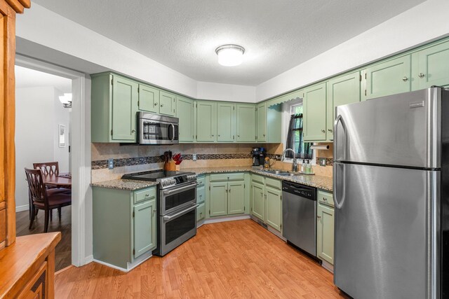 95 Olympic Cir, Chanhassen, MN 55317 - kitchen featuring stainless steel appliances, green cabinets, a sink, light wood-style floors, and a textured ceiling