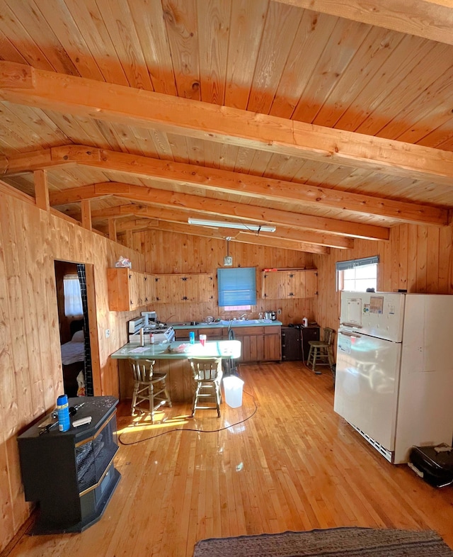 17353 Pine Dr NW, Angle Inlet, MN 56711 - kitchen featuring freestanding refrigerator, light wood-style floors, wooden walls, wooden ceiling, and a wood stove