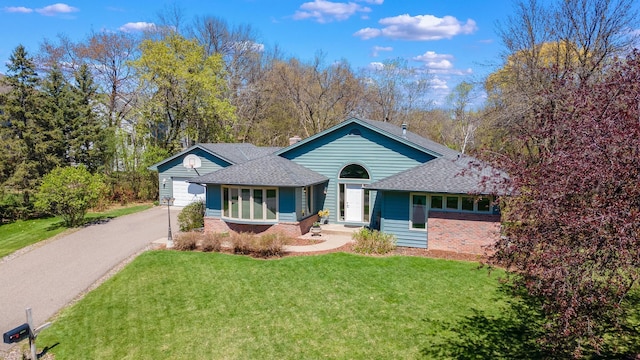 ranch-style house with roof with shingles, aphalt driveway, brick siding, and a front yard