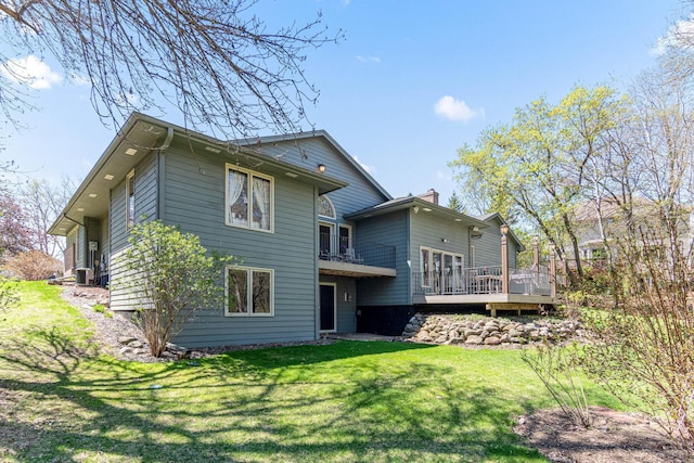 back of house featuring a yard, a chimney, a wooden deck, and central AC
