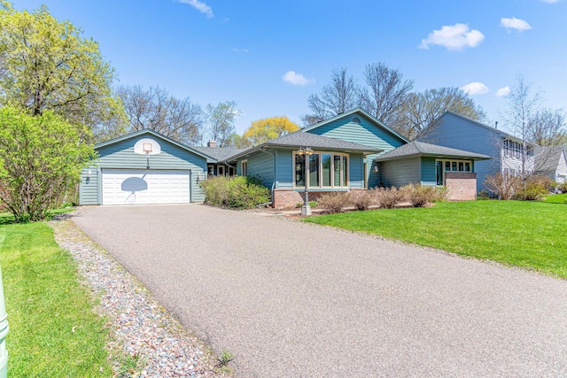 ranch-style home featuring a front lawn, brick siding, aphalt driveway, and an attached garage