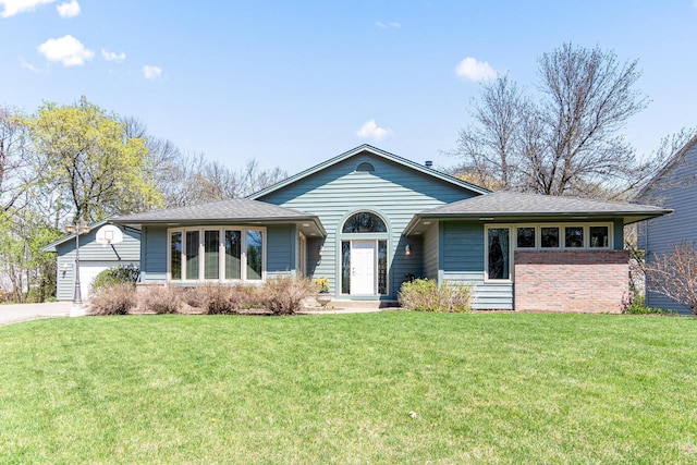 view of front of property featuring a front yard, a shingled roof, a garage, and driveway