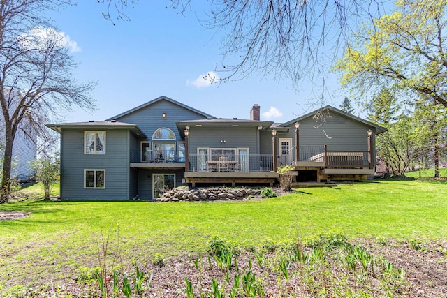 back of house with a wooden deck, a chimney, and a lawn